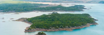 Vue panoramique sur la plage avec des eaux turquoise et des collines.